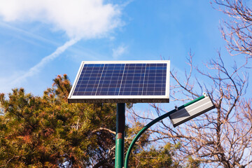 A solar panel is installed on a street lamp post in a park.