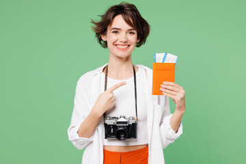 Wall Mural - Traveler happy smiling fun woman wear casual clothes hold point on passport ticket isolated on plain green background. Tourist travel abroad in free spare time rest getaway. Air flight trip concept.