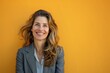 © CogniLens - Portrait of a smiling woman in her 40s wearing a professional suit jacket over pastel orange background