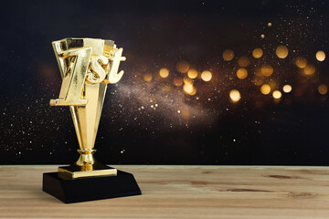Wall Mural - golden trophy on wooden table and dark background. idea of award and success