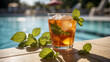 © Kraiwit - frosty glass of iced tea with mint leaves, placed on the edge of a swimming pool. The sunny sky should reflect off the water