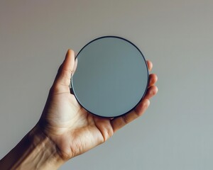 Poster - A hand holding a small mirror against a high-key background, creating a minimalistic scene with subtle reflections.