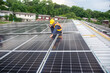 © sirisakboakaew - A solar panel installation company employee assembles a photovoltaic system on the roof.
