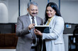 © GAJENDRRA BHATI  - Young indian professional woman showing businessman company growth using digital tablet in corporate office. workplace and business concept.
