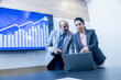 © GAJENDRRA BHATI  - young indian professional woman with businessman discussing trading and stocks on laptop in office. stock broker, business and finance concept.