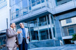 © GAJENDRRA BHATI  - two senior indian business person discussing about company growth in front of modern, corporate glass office. success, growth and workplace concept.
