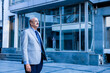 © GAJENDRRA BHATI  - senior indian business person standing in front of modern, corporate glass office. success, growth and workplace concept.