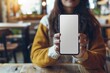 © yanlong - Close-Up of Woman Holding Smartphone Mockup in Coffee Shop with Blank Space for Advertising
