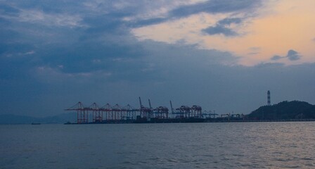 Poster - Serene view of a port with cranes under a cloudy evening sky by the water