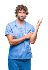 Poster - Handsome hispanic surgeon doctor man over isolated background with a big smile on face, pointing with hand and finger to the side looking at the camera.