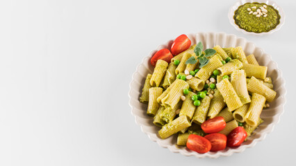 Wall Mural - Delicious pasta with fresh basil pesto, green peas, cherry tomatoes and cheese. Copy space