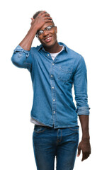 Sticker - Young african american man over isolated background surprised with hand on head for mistake, remember error. Forgot, bad memory concept.