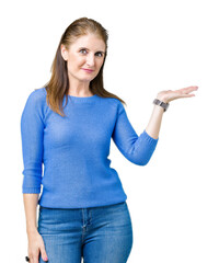 Sticker - Beautiful middle age mature woman wearing winter sweater over isolated background smiling cheerful presenting and pointing with palm of hand looking at the camera.