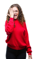 Poster - Beautiful brunette curly hair young girl wearing glasses and winter sweater over isolated background covering one eye with hand with confident smile on face and surprise emotion.