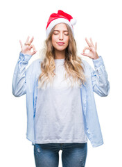 Sticker - Beautiful young blonde woman wearing christmas hat over isolated background relax and smiling with eyes closed doing meditation gesture with fingers. Yoga concept.