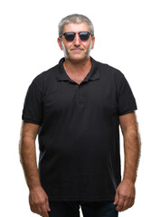 Poster - Handsome senior man wearing sunglasses over isolated background with serious expression on face. Simple and natural looking at the camera.