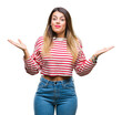 © Krakenimages.com - Young beautiful woman casual stripes winter sweater over isolated background clueless and confused expression with arms and hands raised. Doubt concept.