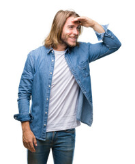 Sticker - Young handsome man with long hair over isolated background very happy and smiling looking far away with hand over head. Searching concept.