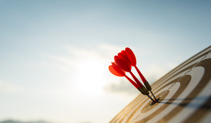 Canvas Print - Close up shot red darts arrows in the target center on dark blue sky background. Business target or goal success and winner concept.