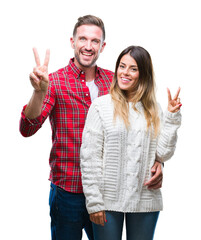 Wall Mural - Young couple in love wearing winter sweater over isolated background smiling with happy face winking at the camera doing victory sign. Number two.