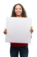 young hispanic woman holding blank banner with a happy face standing and smiling with a confident sm