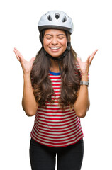 Wall Mural - Young arab cyclist woman wearing safety helmet over isolated background celebrating mad and crazy for success with arms raised and closed eyes screaming excited. Winner concept