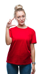 Wall Mural - Young blonde woman wearing glasses over isolated background smiling and confident gesturing with hand doing size sign with fingers while looking and the camera. Measure concept.