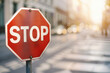 © Oranuch - Red octagonal stop sign with blurred road and cars in the background