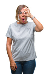 Wall Mural - Middle age senior hispanic woman wearing glasses over isolated background doing ok gesture shocked with surprised face, eye looking through fingers. Unbelieving expression.