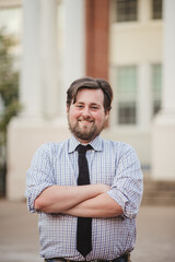 Young Gen Z Business Man in a Blue shirt with a black tie in an academic setting. 