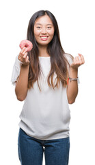 Canvas Print - Young asian woman eating donut over isolated background screaming proud and celebrating victory and success very excited, cheering emotion