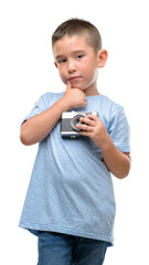 Sticker - Dark haired little child holding vintage camera serious face thinking about question, very confused idea