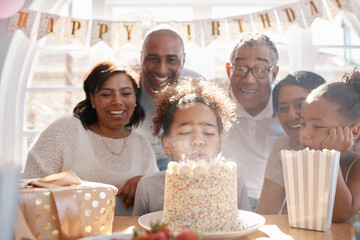 Wall Mural - Girl, birthday cake and blowing candles with family for fun together, happiness and annual milestone in home. Child, event or party for celebration of growth with gift, dessert food and generations