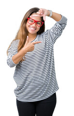 Sticker - Young beautiful brunette woman wearing stripes sweater and red glasses over isolated background smiling making frame with hands and fingers with happy face. Creativity and photography concept.