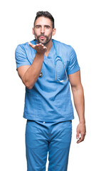 Poster - Handsome young doctor surgeon man over isolated background looking at the camera blowing a kiss with hand on air being lovely and sexy. Love expression.