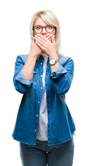 Canvas Print - Young beautiful blonde woman wearing glasses over isolated background shocked covering mouth with hands for mistake. Secret concept.