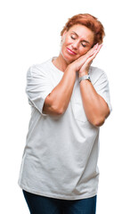 Wall Mural - Atrractive senior caucasian redhead woman over isolated background sleeping tired dreaming and posing with hands together while smiling with closed eyes.