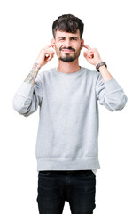 Sticker - Young handsome man wearing sweatshirt over isolated background covering ears with fingers with annoyed expression for the noise of loud music. Deaf concept.