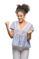 Canvas Print - Young afro american woman over isolated background very happy and excited doing winner gesture with arms raised, smiling and screaming for success. Celebration concept.