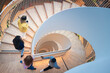 © Johnér - High angle view of colleagues moving up on spiral staircase in office