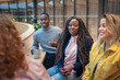 © Johnér - Smiling coworkers listening to businesswoman in office lobby
