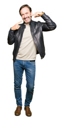 Sticker - Middle age handsome man wearing black leather jacket smiling confident showing and pointing with fingers teeth and mouth. Health concept.