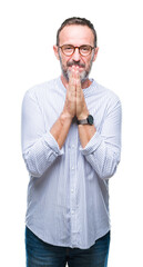 Poster - Middle age hoary senior man wearing glasses over isolated background praying with hands together asking for forgiveness smiling confident.