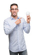 © Krakenimages.com - Handsome young man holding lightbulb as idea very happy pointing with hand and finger