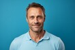 © Markus Schröder - Portrait of a satisfied man in his 40s wearing a sporty polo shirt in soft blue background
