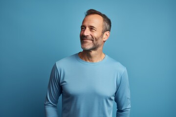 Wall Mural - Portrait of a satisfied man in his 40s showing off a lightweight base layer on soft blue background