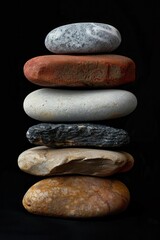 Poster - A stack of smooth pebbles photographed against a black background, studio photography with professional color grading, soft shadows, clean sharp focus, and natural light.