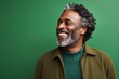 © Markus Schröder - Portrait of a satisfied afro-american man in his 50s wearing a chic cardigan over soft green background