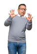 © Krakenimages.com - Middle age bussines arab man wearing glasses over isolated background afraid and terrified with fear expression stop gesture with hands, shouting in shock. Panic concept.