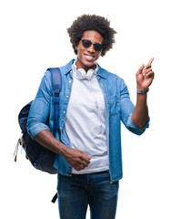 Poster - Afro american man wearing headphones and backpack over isolated background very happy pointing with hand and finger to the side